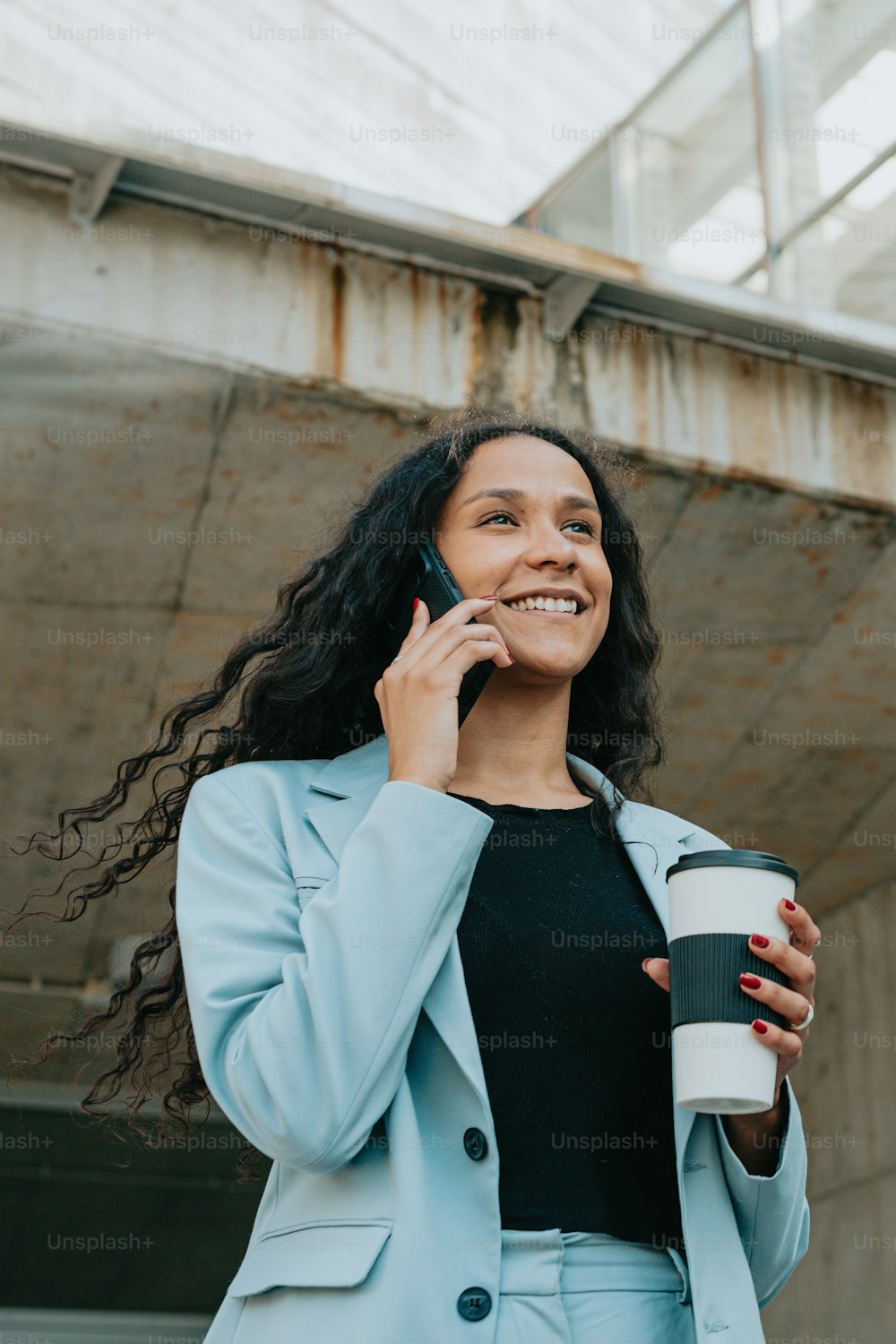 a woman holding a coffee cup and talking on a cell phone