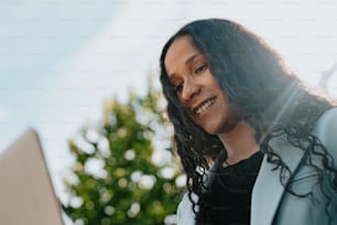 a woman smiles as she looks at her laptop