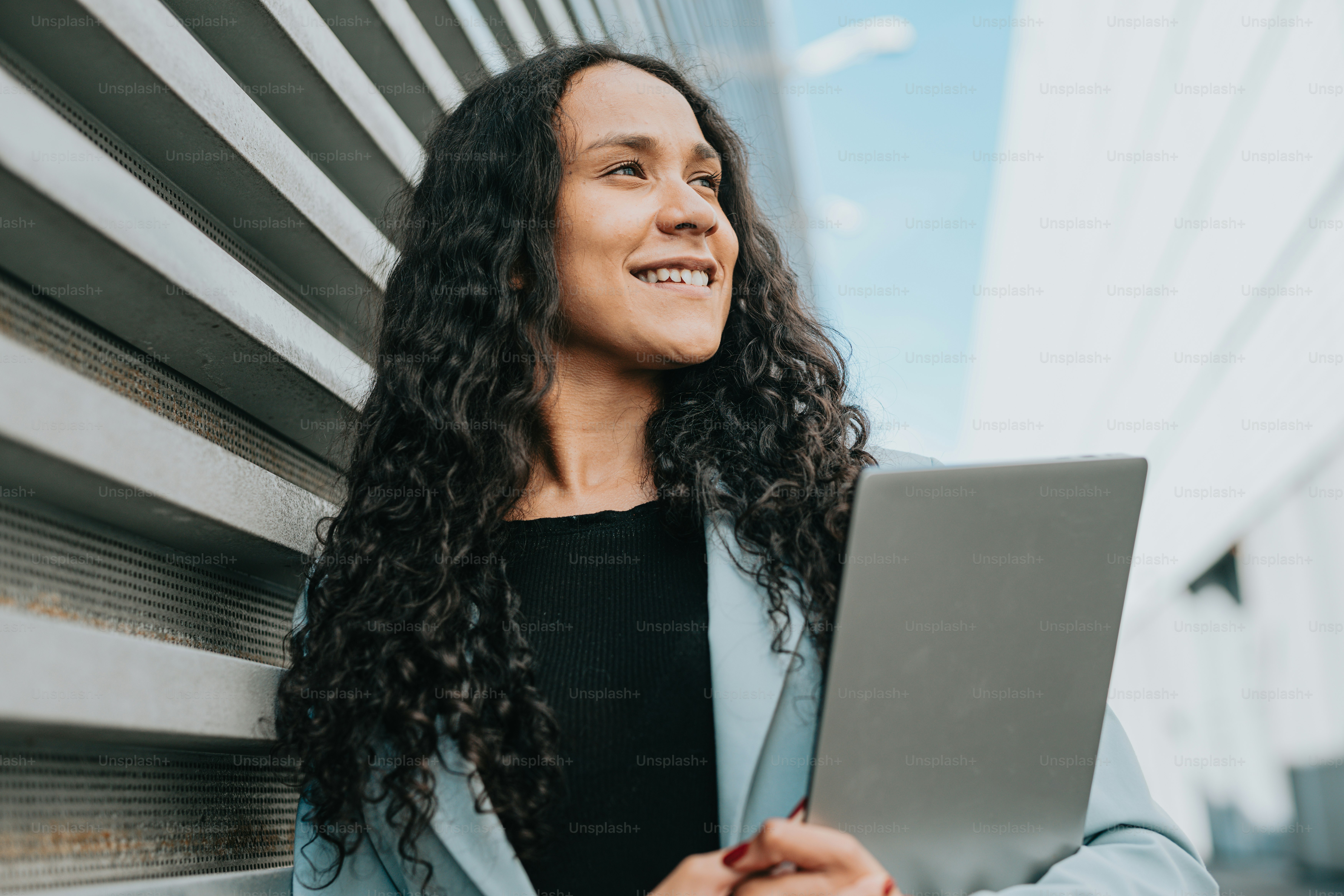 a woman smiles while holding a laptop computer