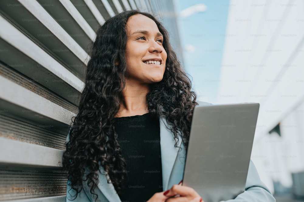 a woman smiles while holding a laptop computer