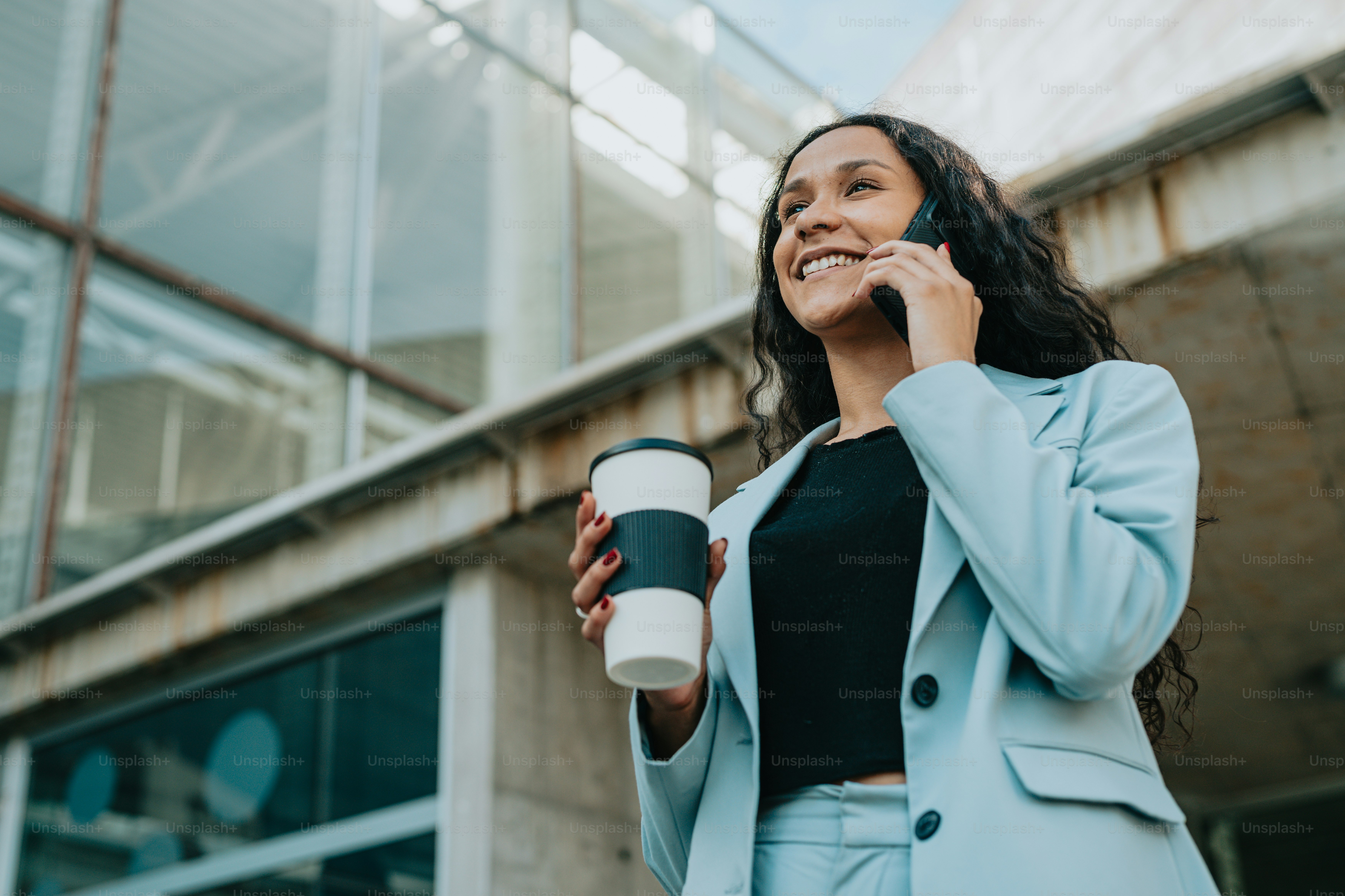 a woman holding a coffee cup and talking on a cell phone