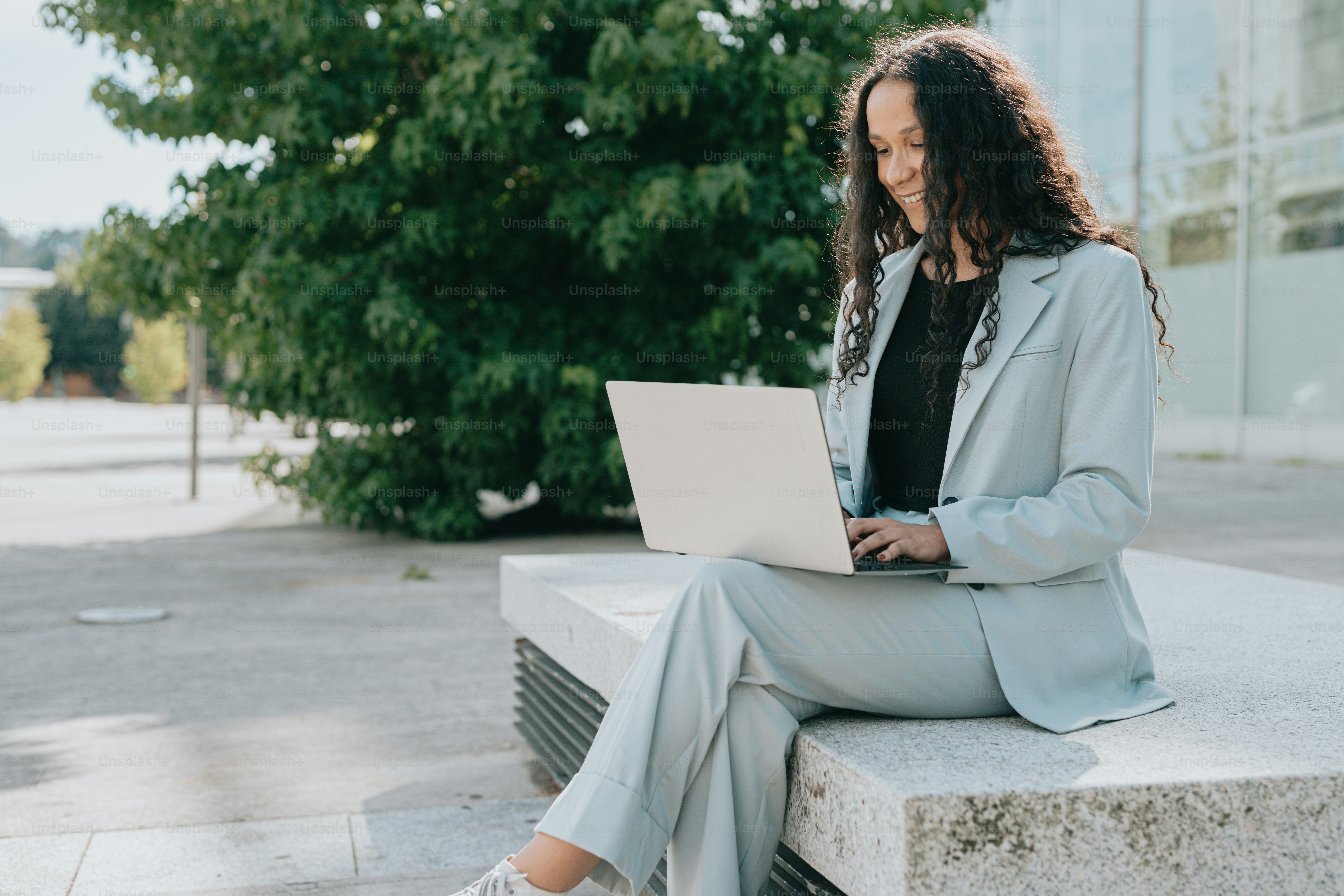 a woman sitting on a bench using a laptop computer