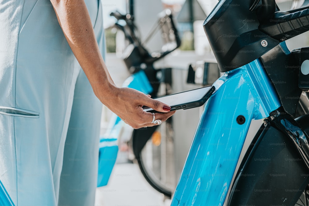 Una persona sosteniendo un teléfono celular junto a una bicicleta azul