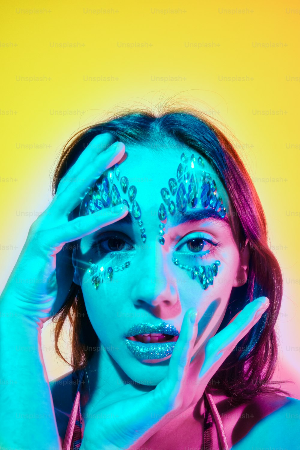 a woman with glitter on her face holding her hands up to her face