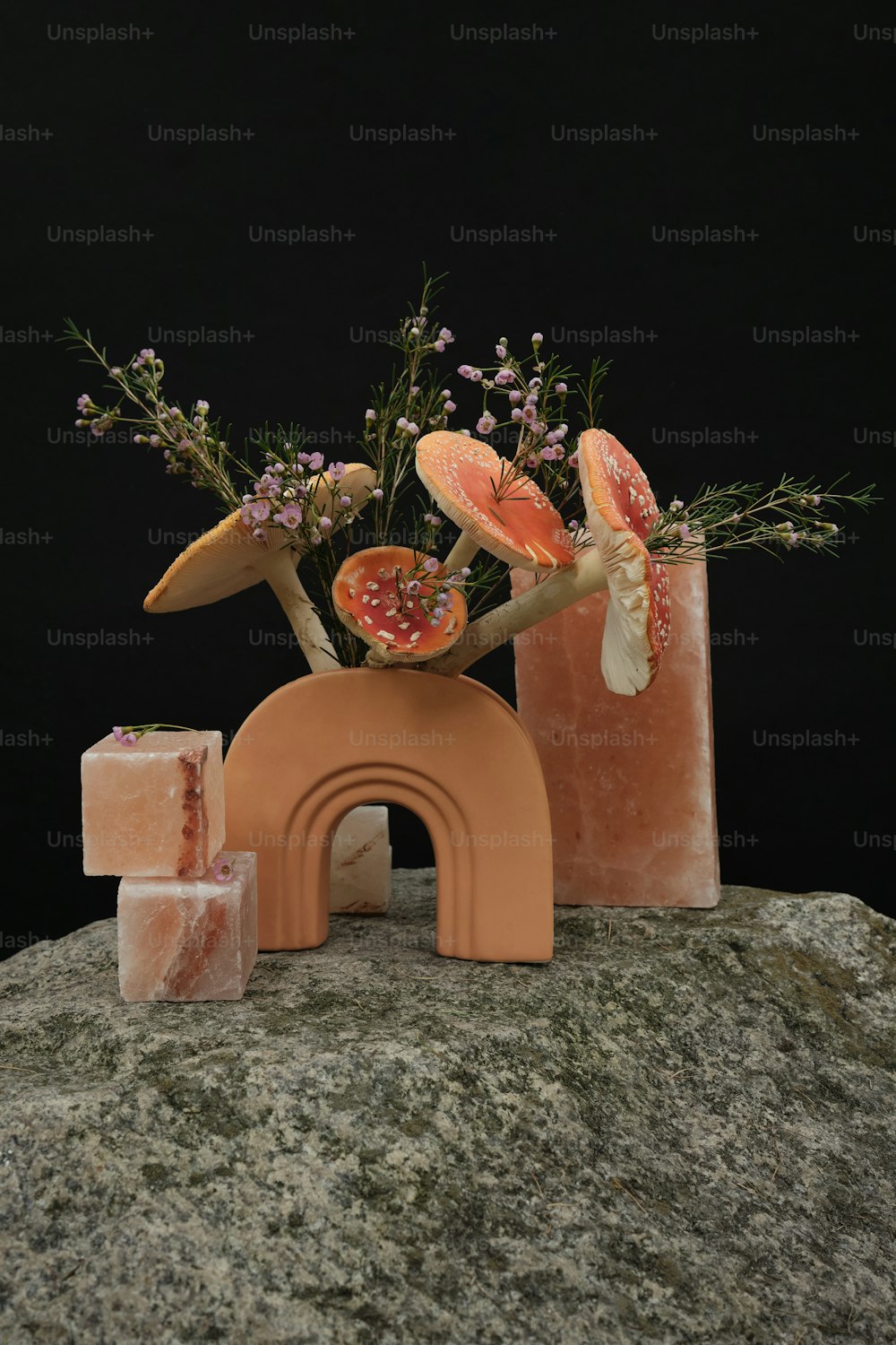 eine Vase mit Blumen und Früchten auf einem Felsen