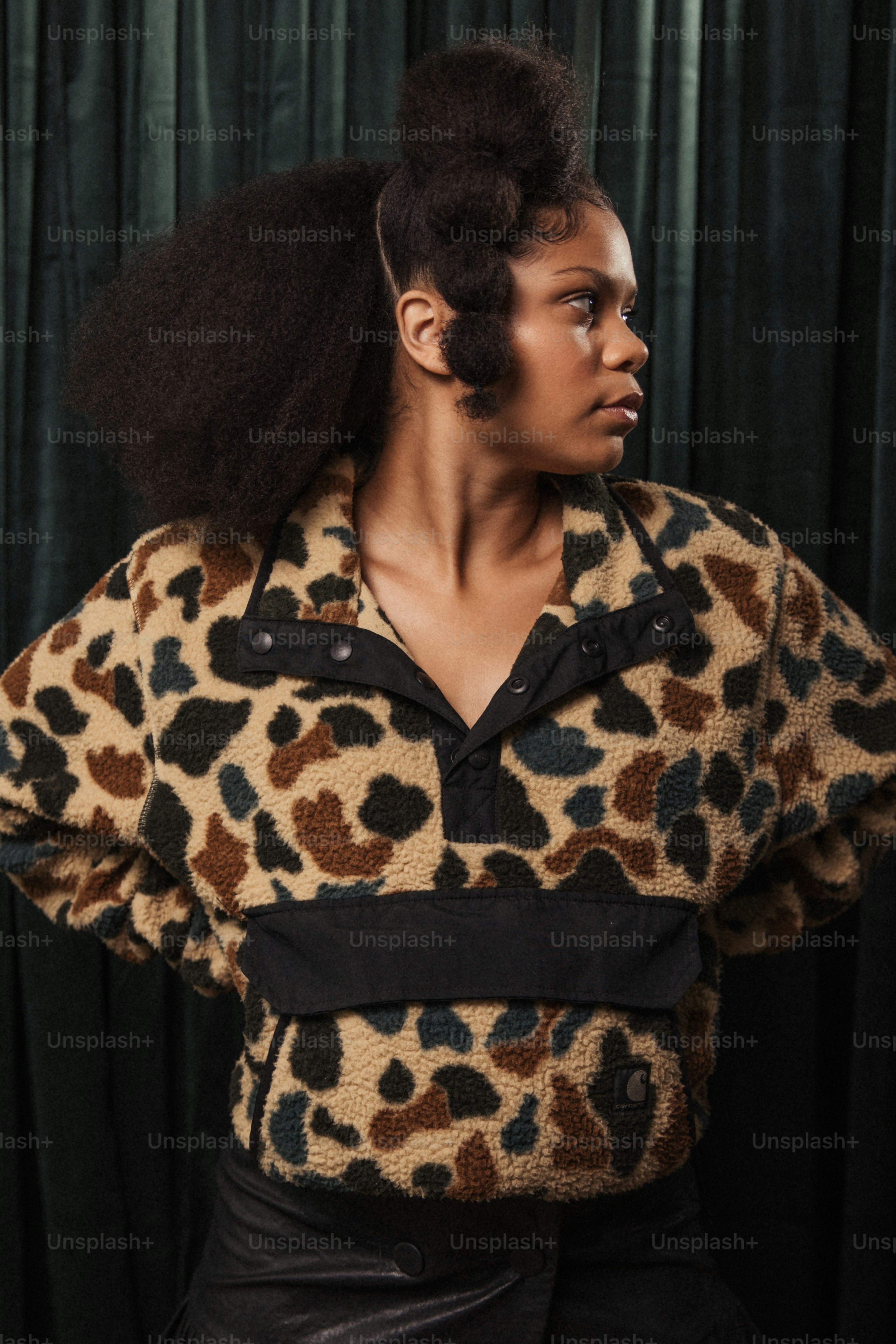 Une femme avec un afro debout devant un rideau