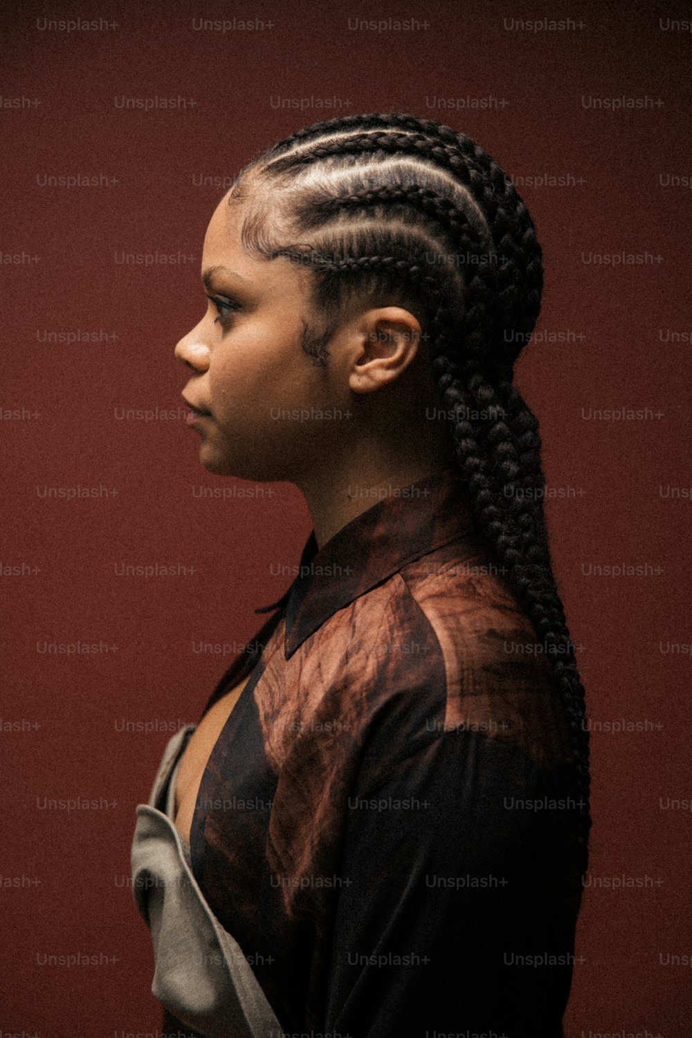a woman with long braids standing in front of a red wall
