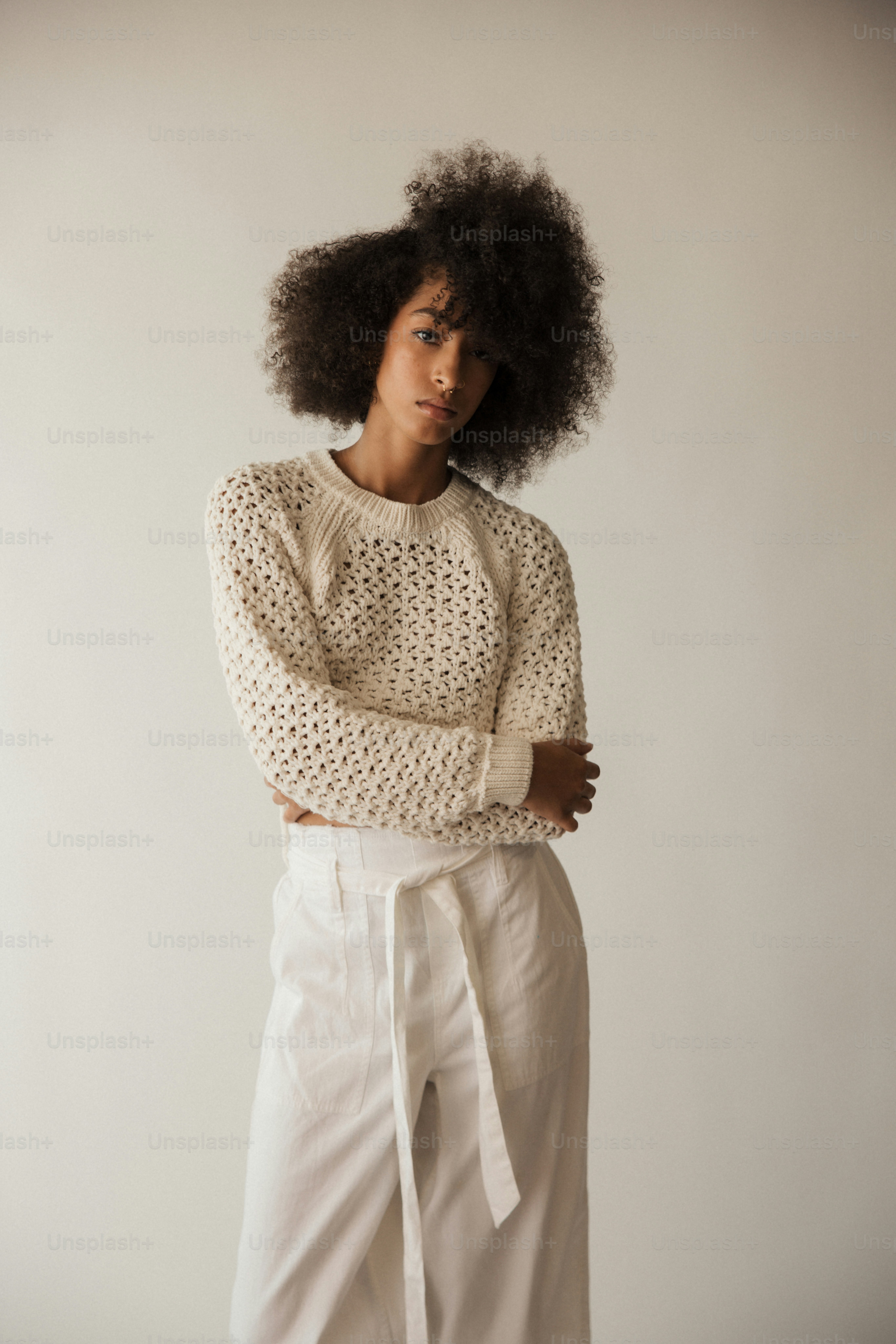 a woman with an afro standing with her arms crossed