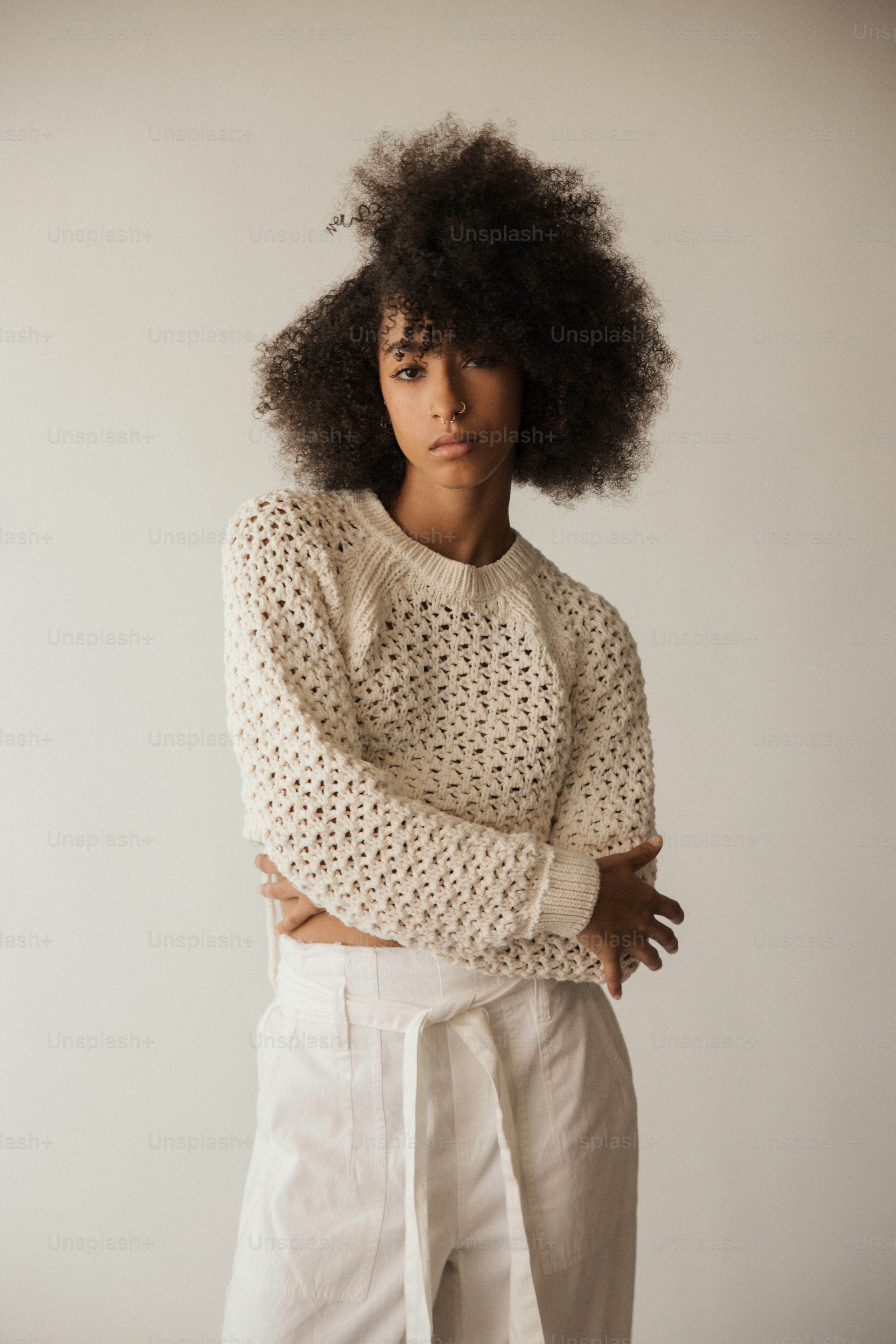 Une femme avec un afro debout, les bras croisés