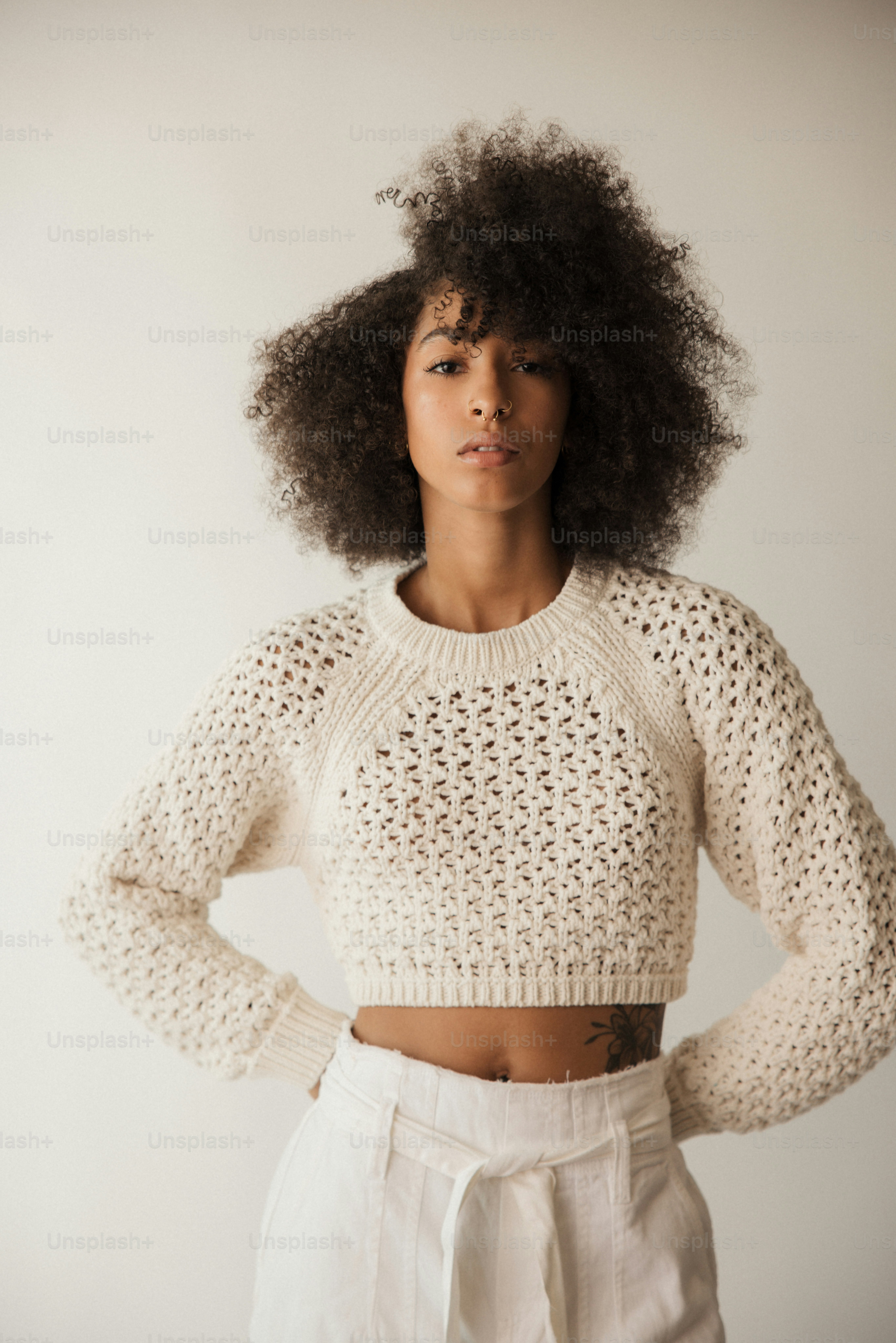 Une femme avec un afro debout devant un mur blanc