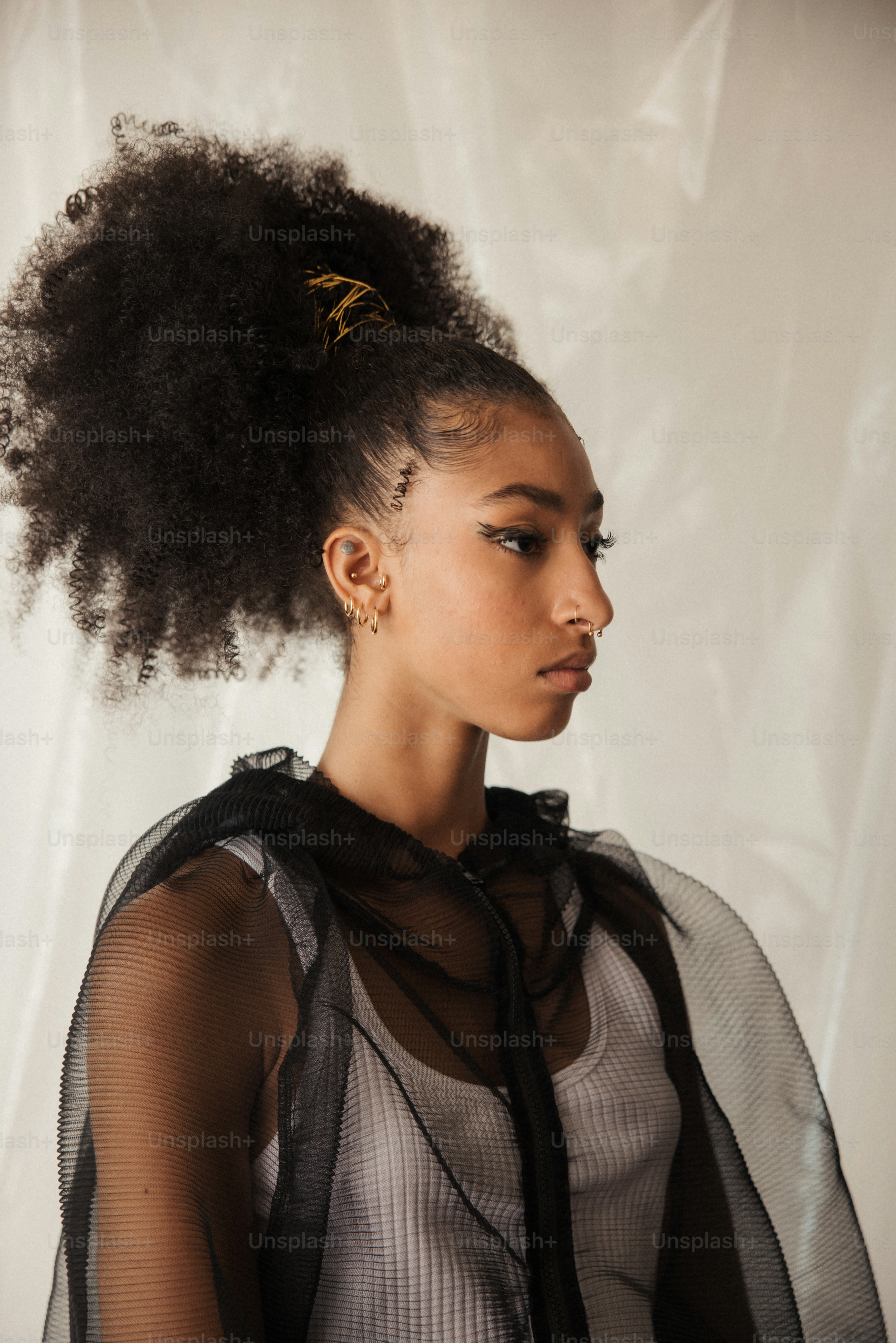 Une femme avec un afro debout devant un fond blanc