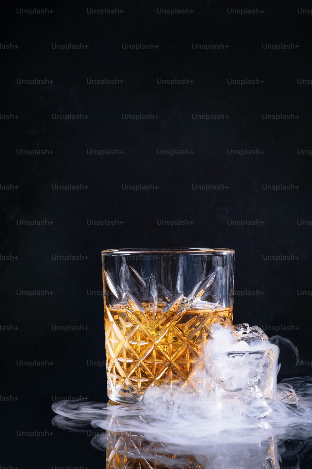 un vaso de whisky con hielo sobre fondo negro