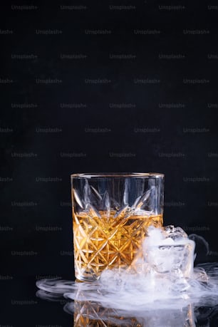 a glass of whiskey with ice on a black background