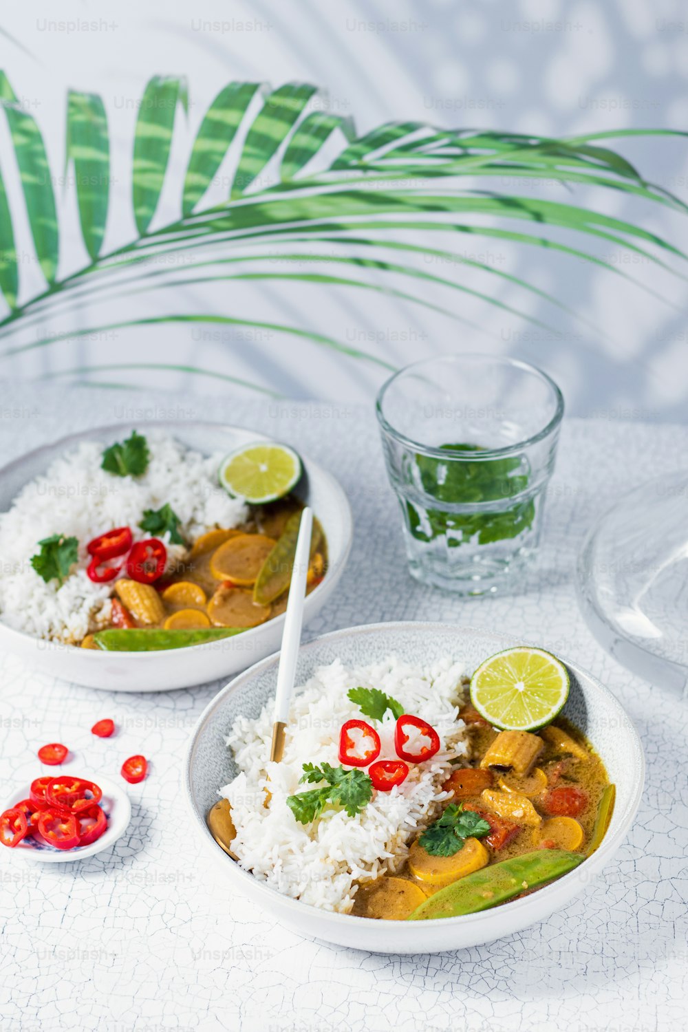 two white bowls filled with food next to a glass of water