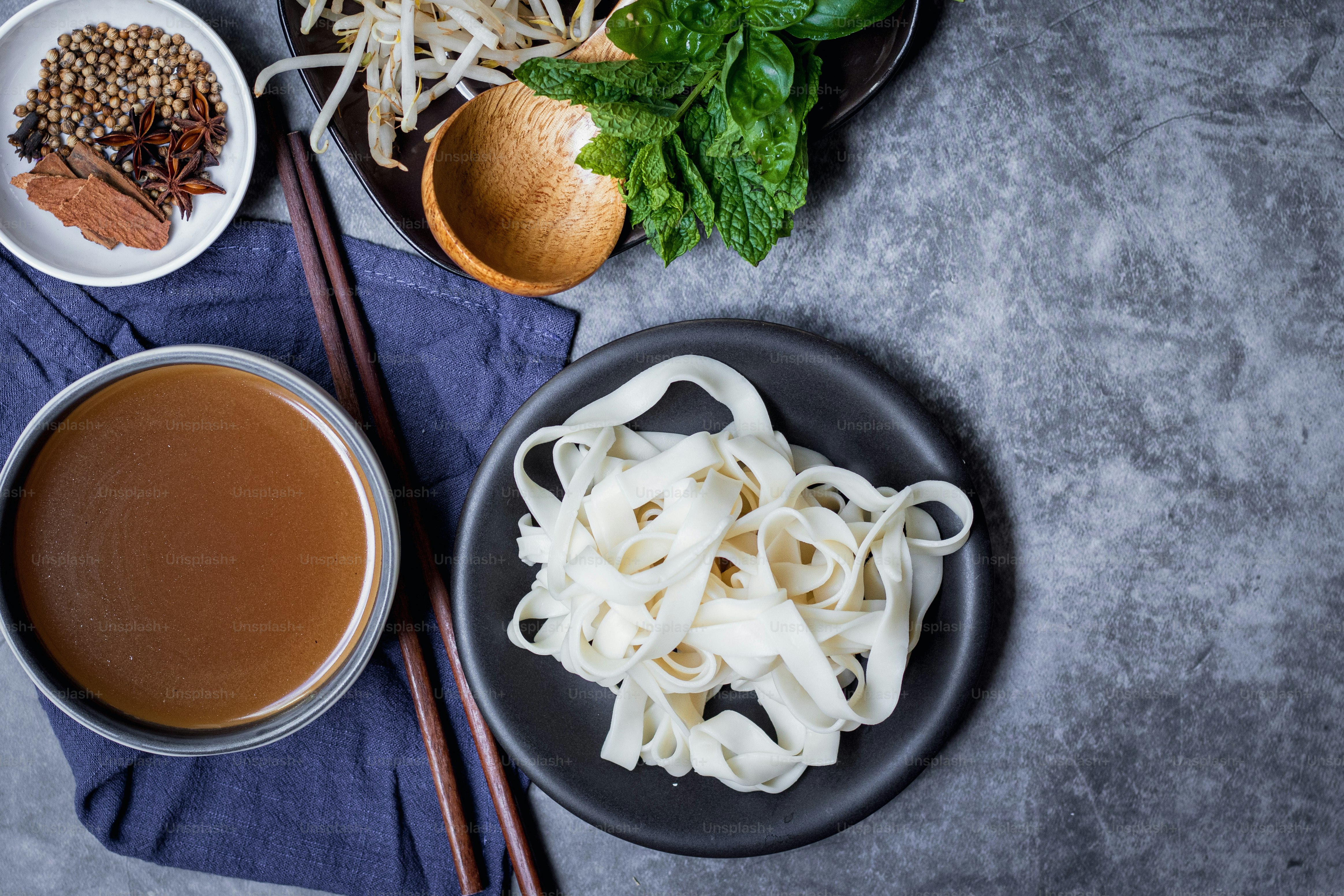 ein Teller Nudeln neben einer Schüssel Suppe und Stäbchen