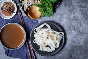 a plate of noodles next to a bowl of soup and chopsticks