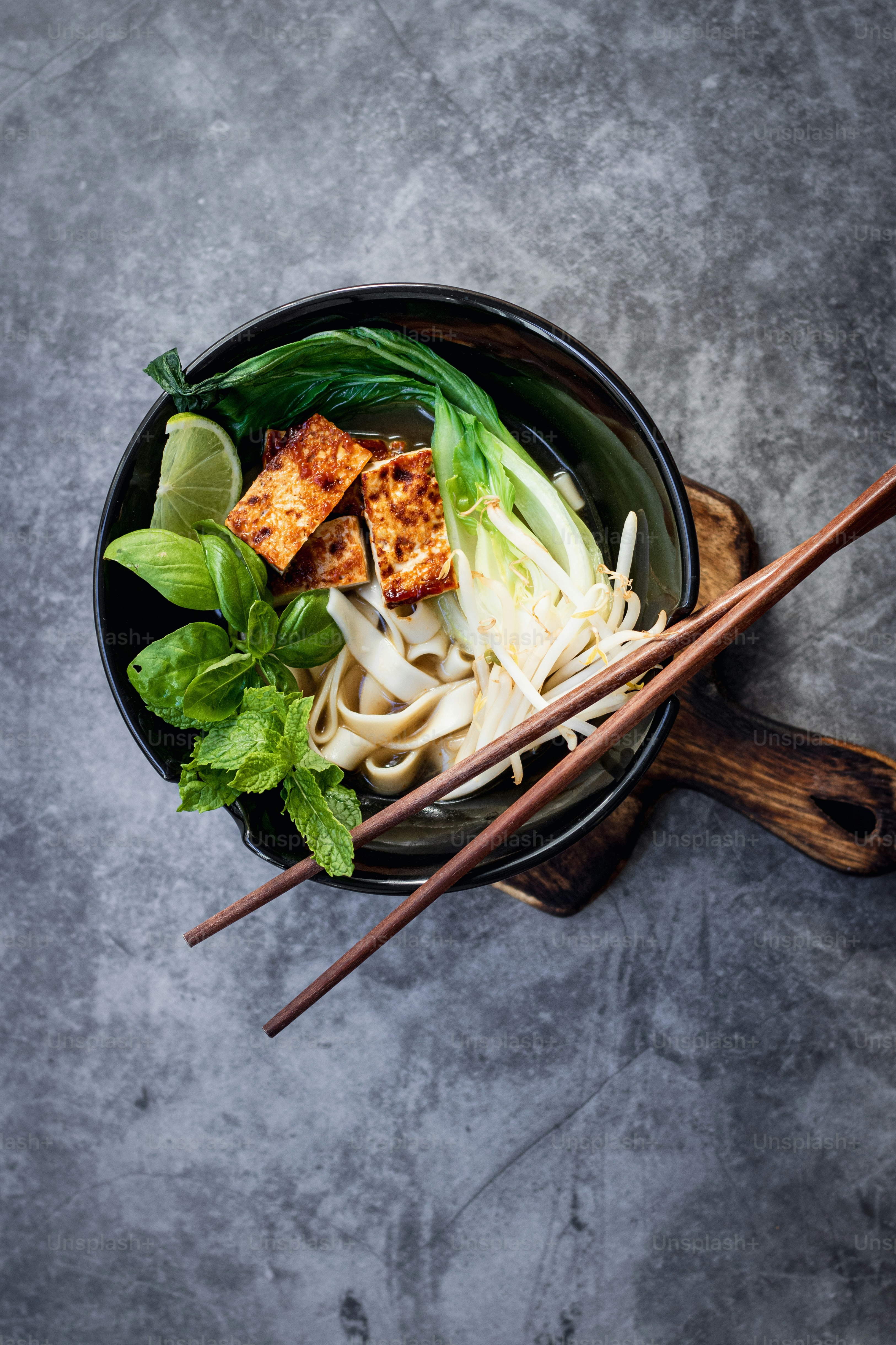 eine Schüssel gefüllt mit Nudeln und Gemüse mit Stäbchen