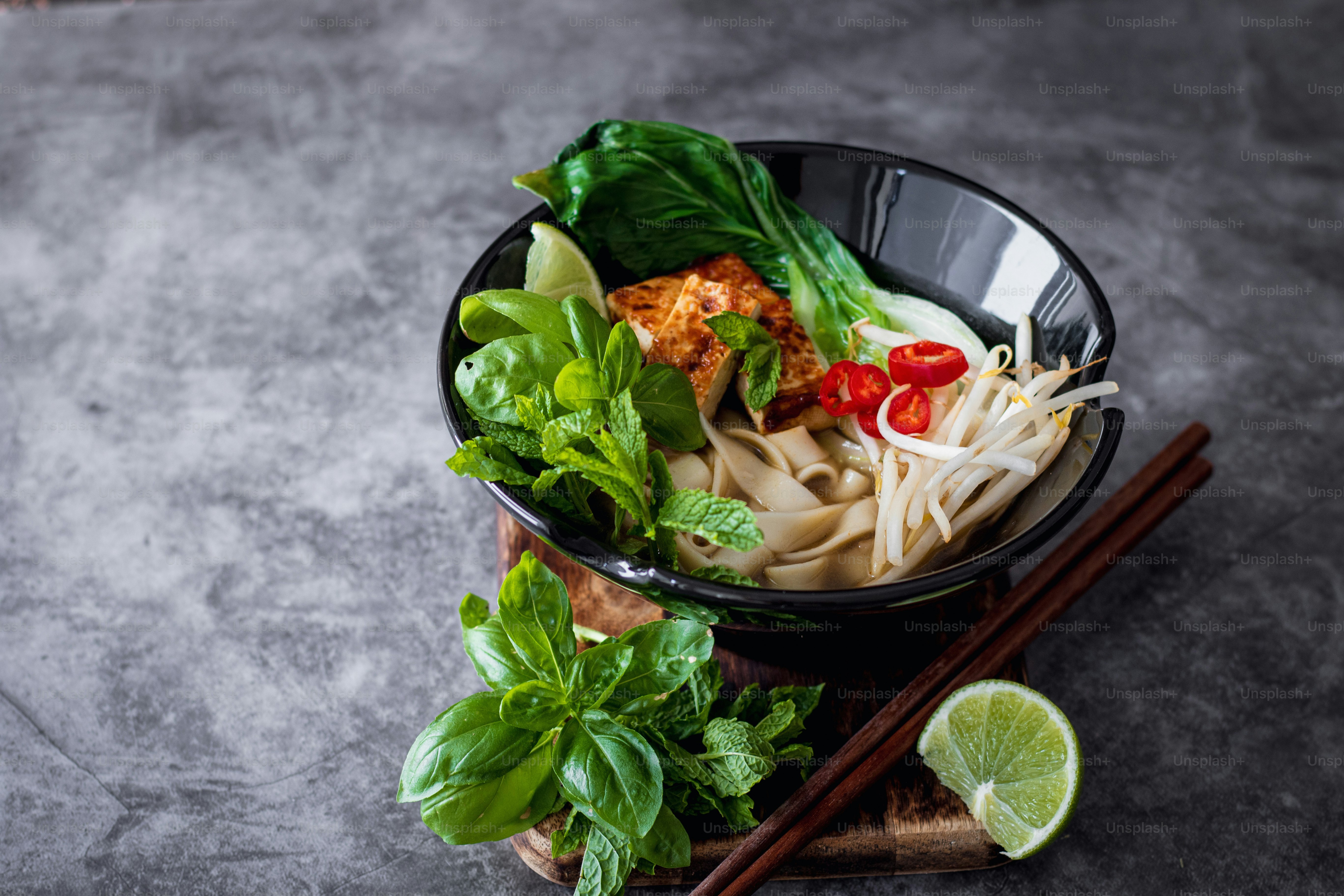a bowl filled with noodles and vegetables next to chopsticks