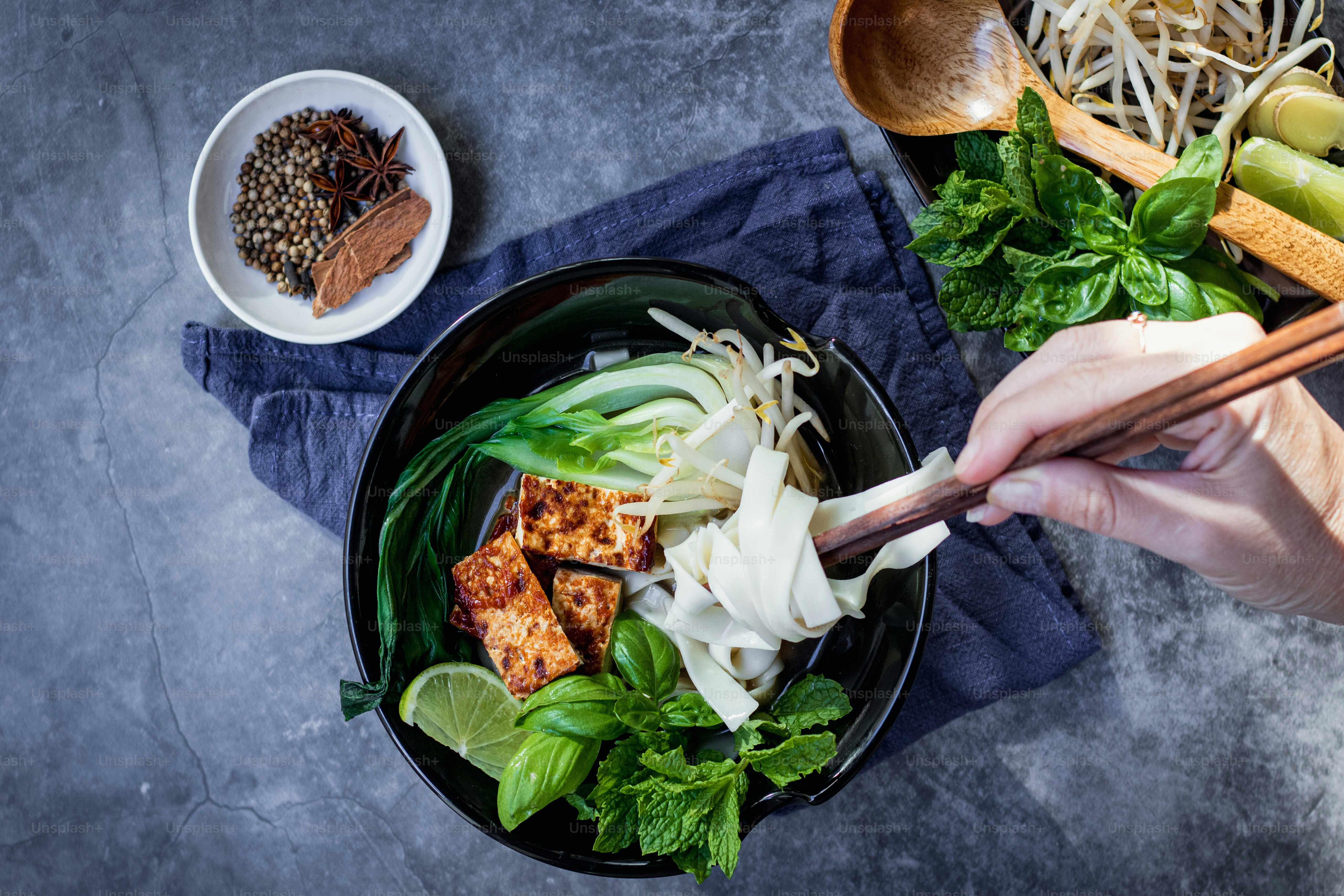 eine Person, die Essstäbchen über eine Schüssel mit Essen hält