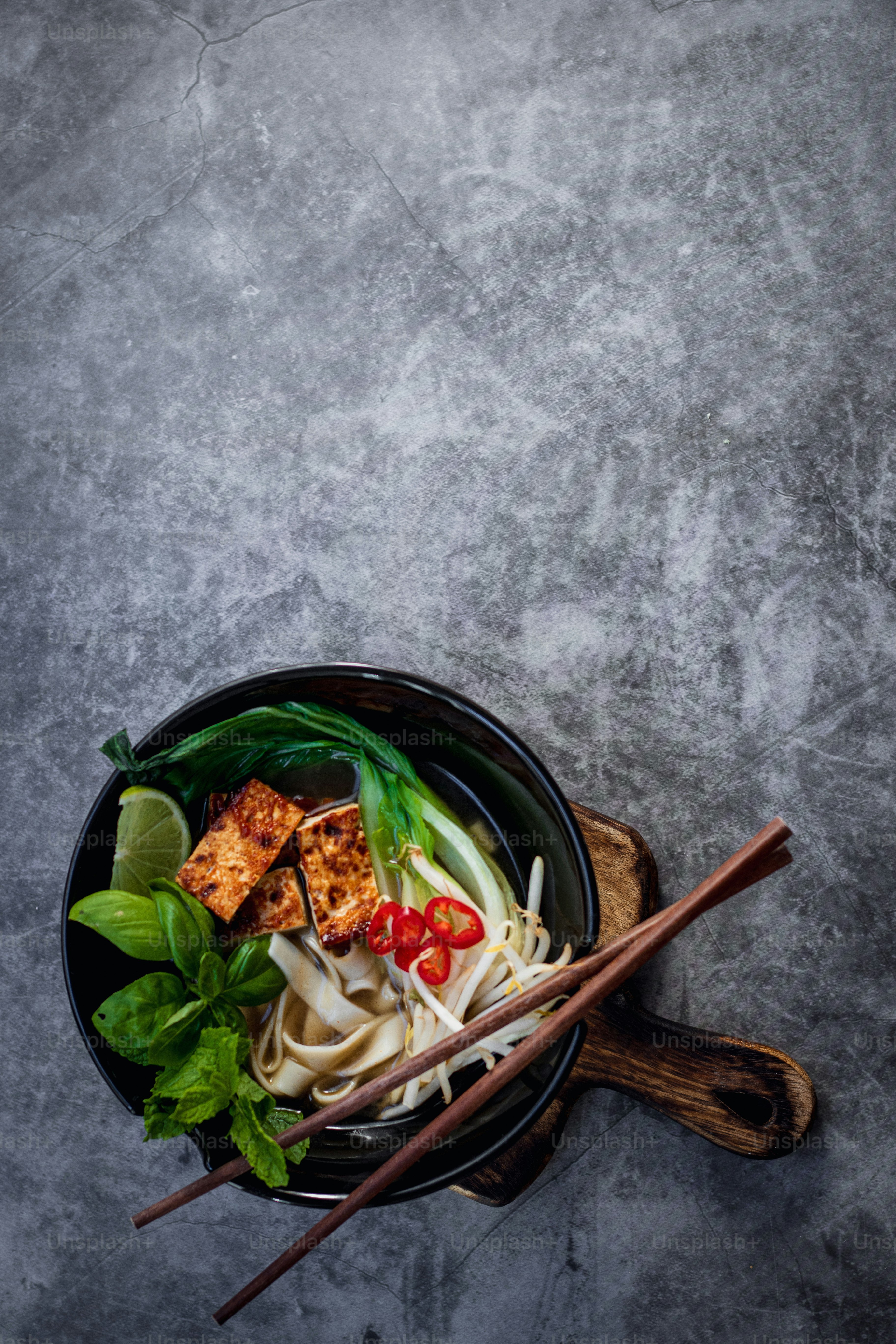 eine Schüssel gefüllt mit Nudeln und Gemüse neben Stäbchen