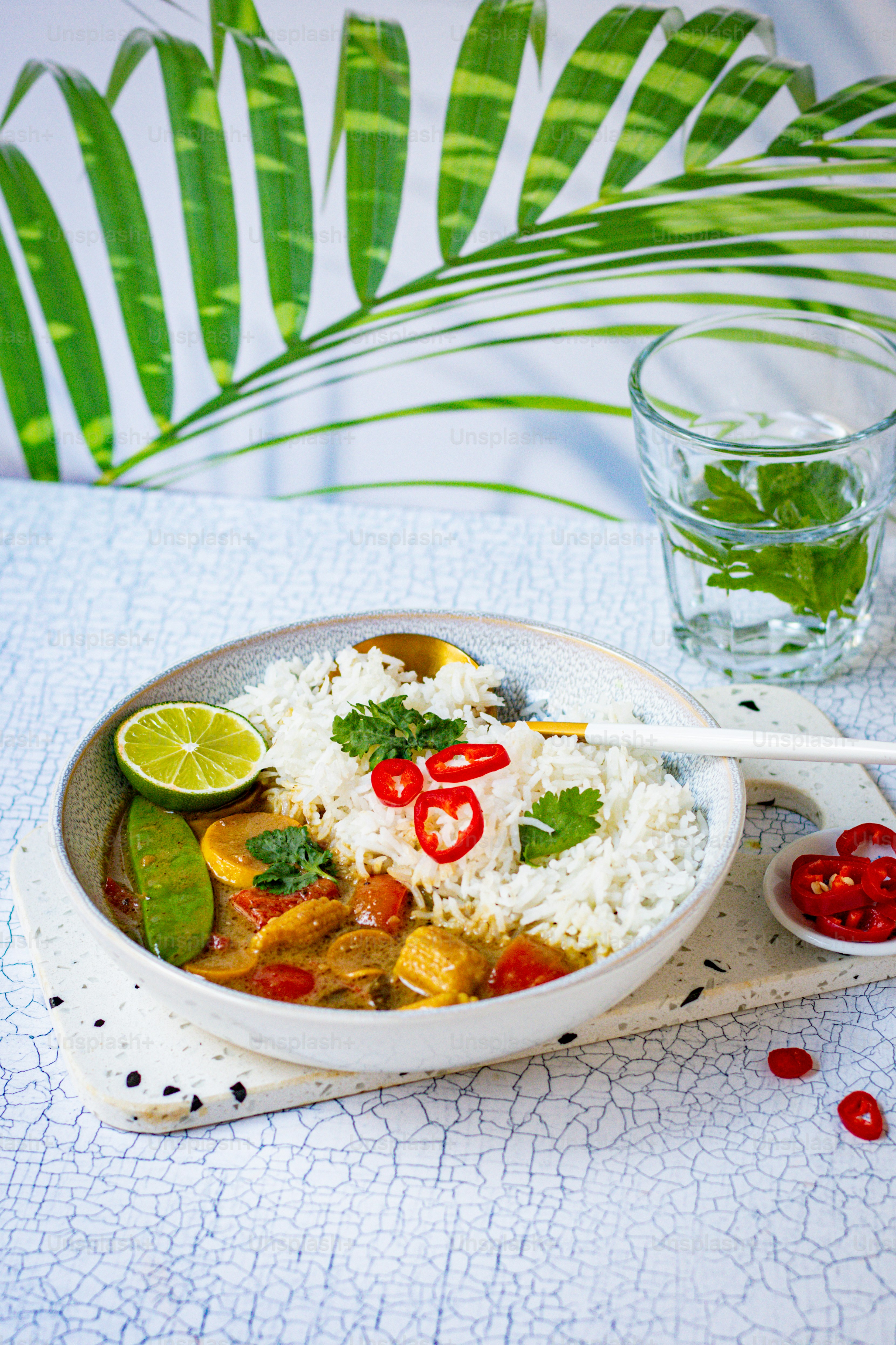 a bowl of rice and vegetables with a glass of water