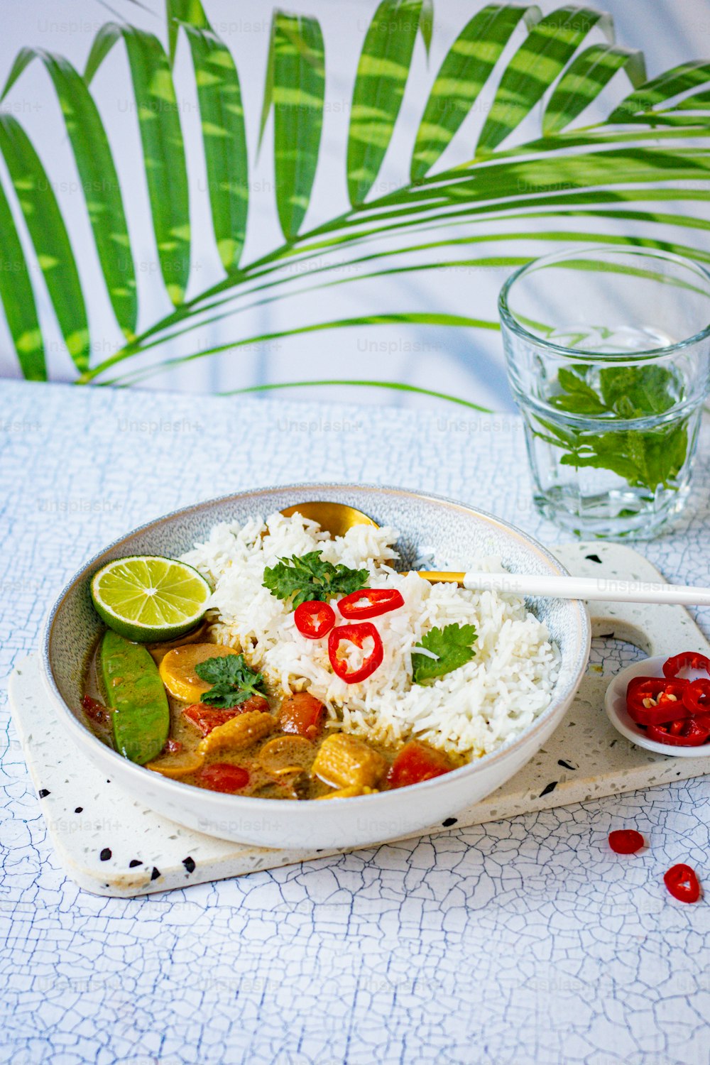 uma tigela de arroz e legumes com um copo de água