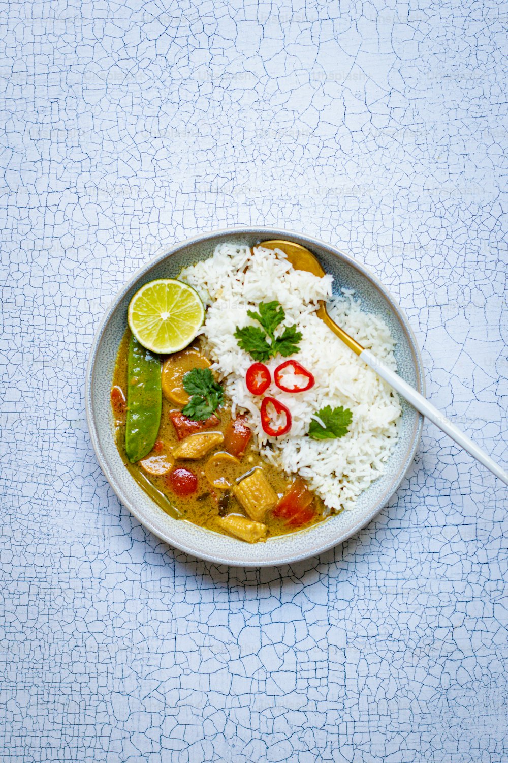 a bowl filled with rice and vegetables next to a spoon