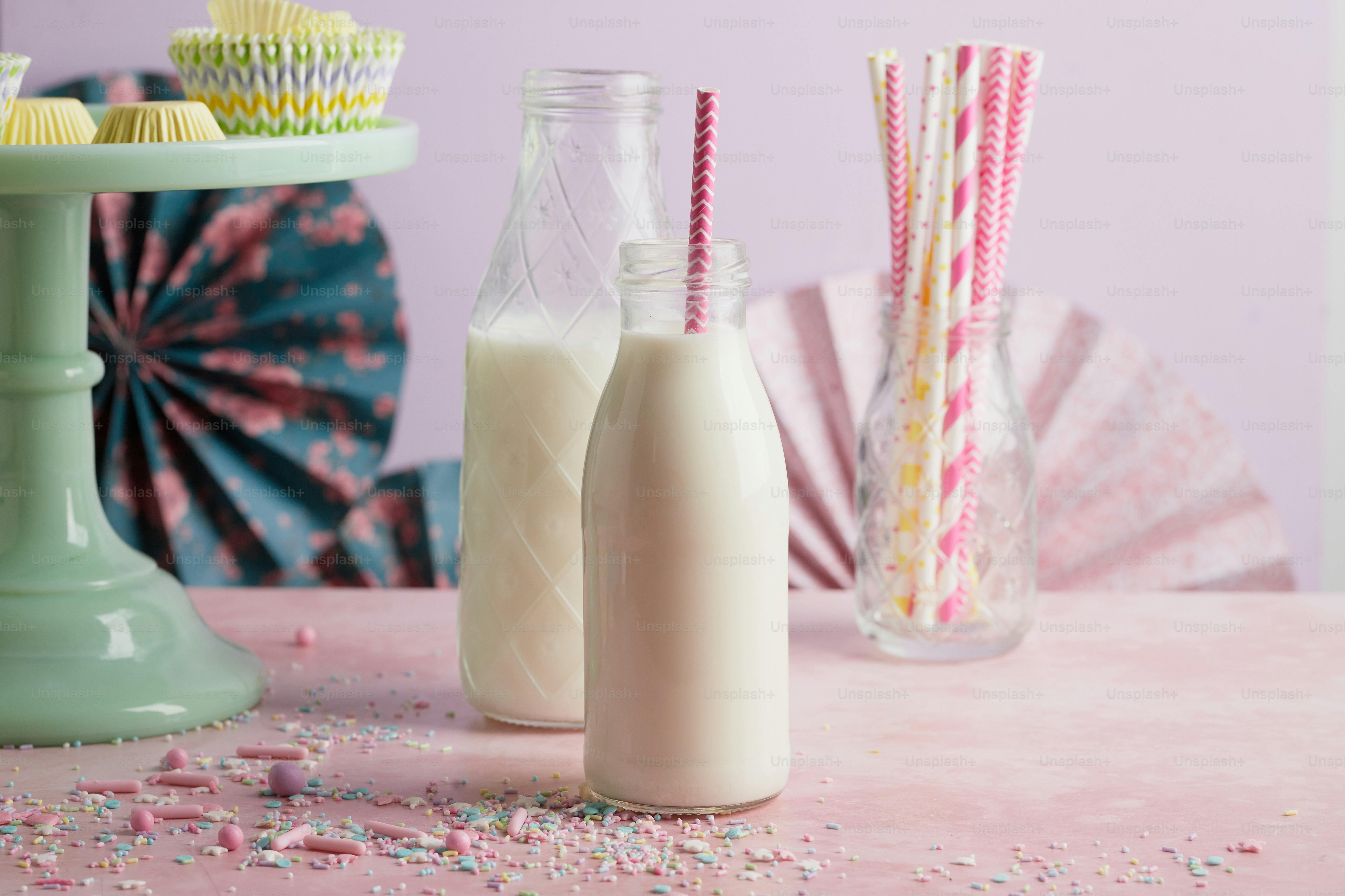 a table topped with bottles of milk and cupcakes