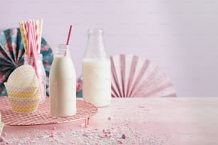 a pink table topped with a bottle of milk and a glass of milk