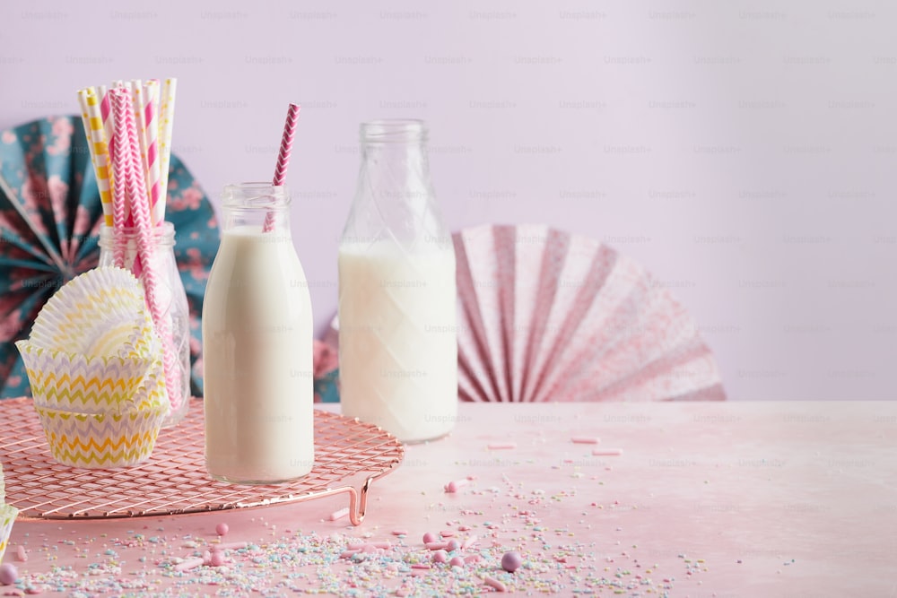 une table rose surmontée d’une bouteille de lait et d’un verre de lait