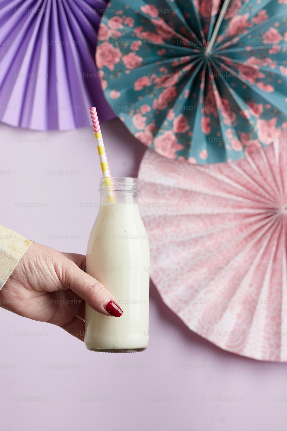 a hand holding a glass of milk next to paper fans
