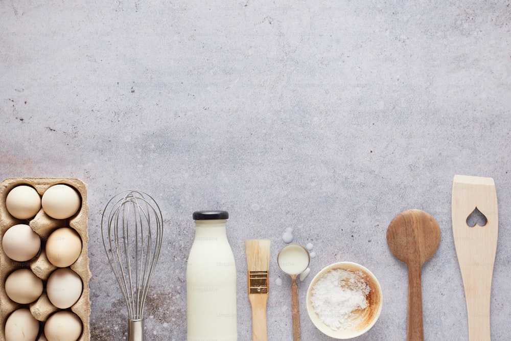 ein Tisch mit Eiern, Milch und Holzlöffeln