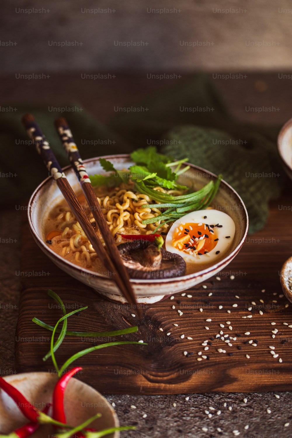 a bowl of ramen with chopsticks on a wooden board