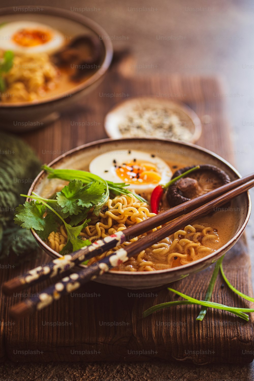 a bowl of ramen with chopsticks on a wooden table