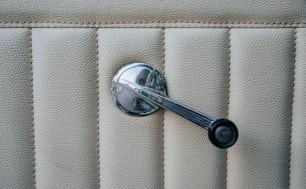a chrome handle on a white leather seat