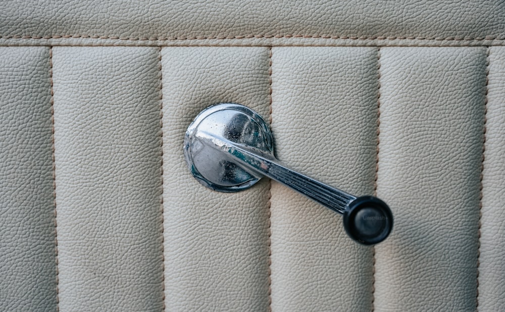 a chrome handle on a white leather seat