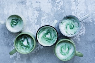 four mugs with green liquid in them on a table