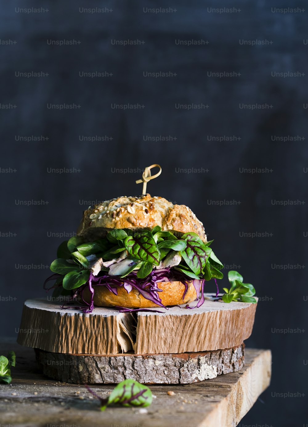a sandwich with lettuce, tomato, and onion on a wooden board