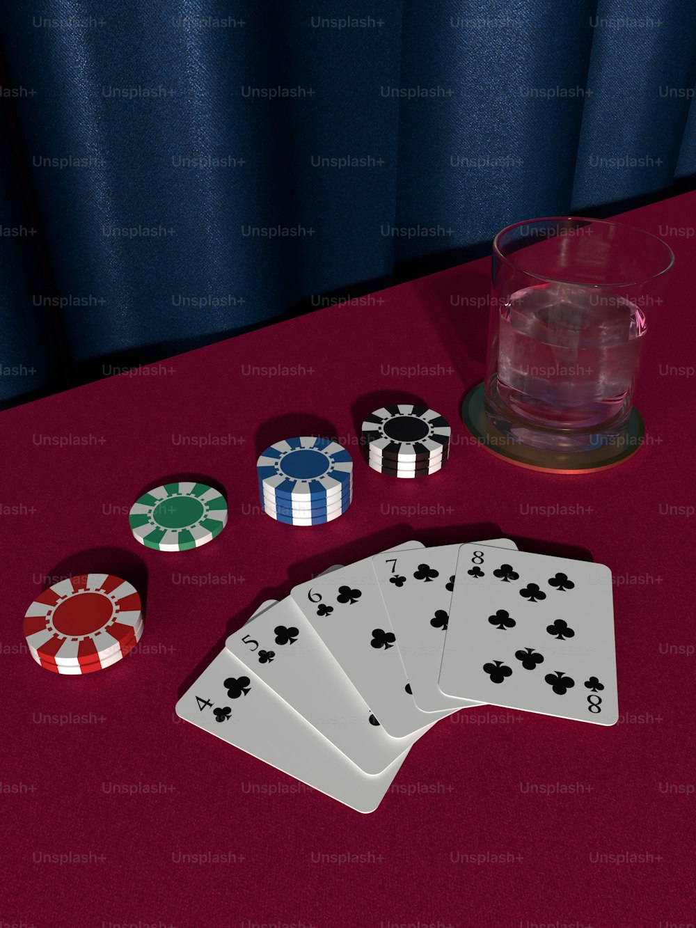 a red table topped with playing cards and a glass of water