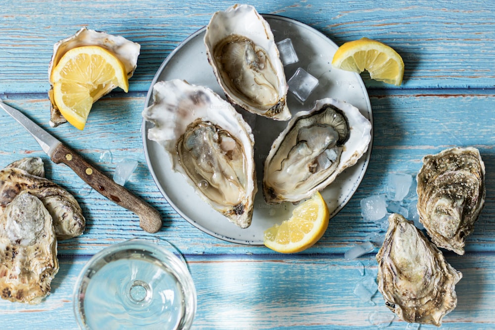 a plate of oysters with lemon wedges and a glass of water