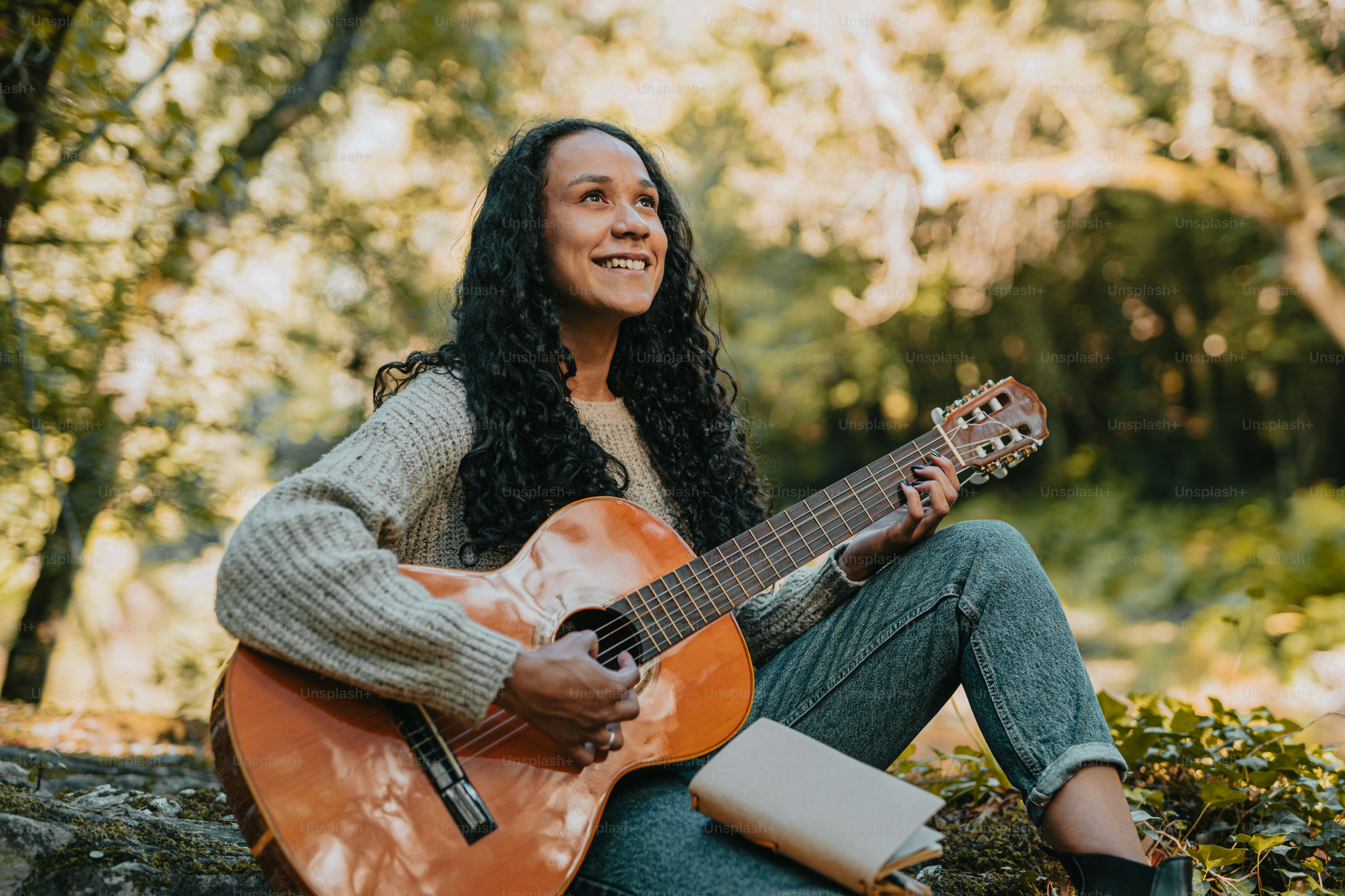 eine frau, die auf dem boden sitzt und gitarre spielt