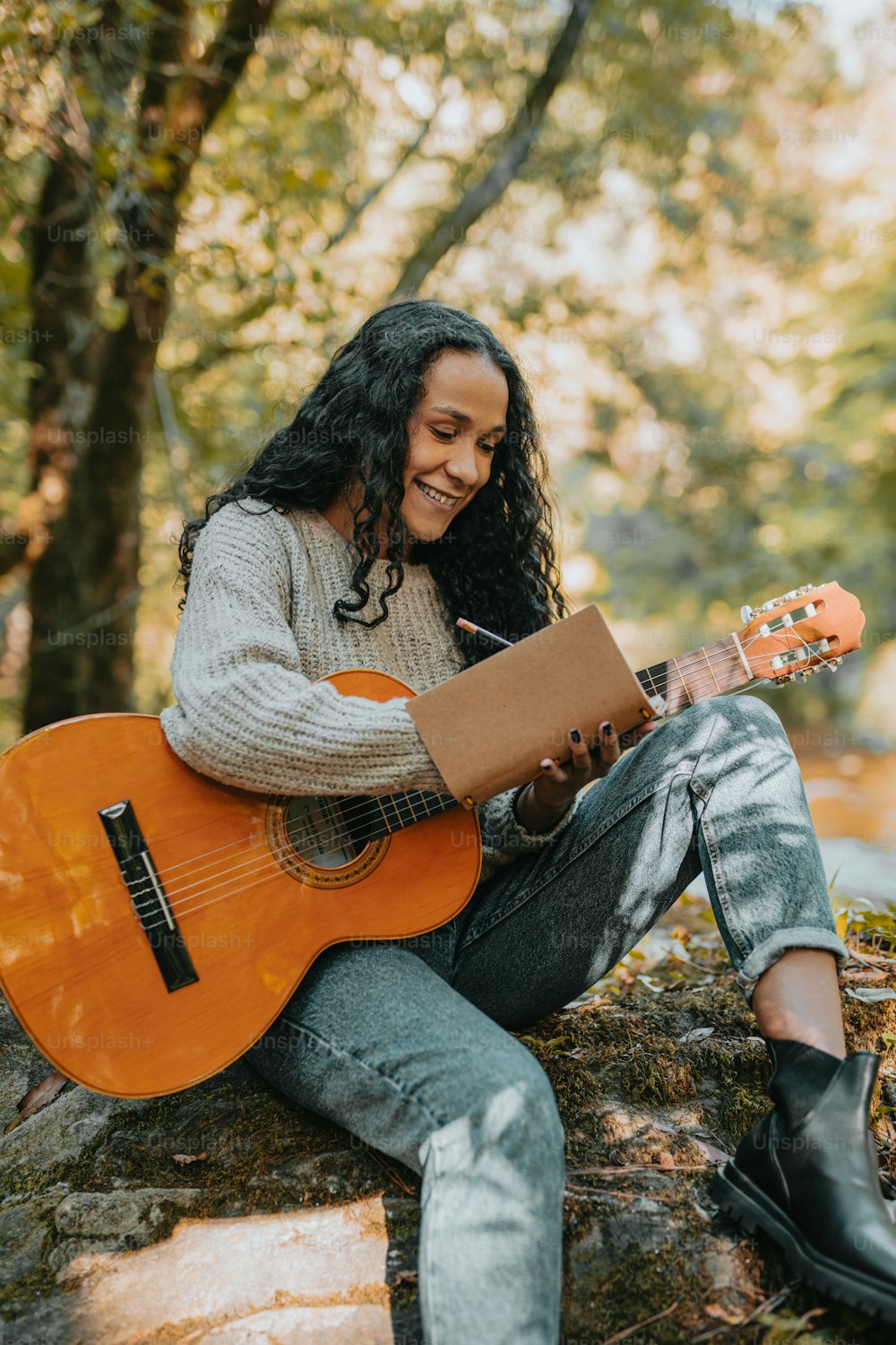 a woman sitting on a rock playing a guitar