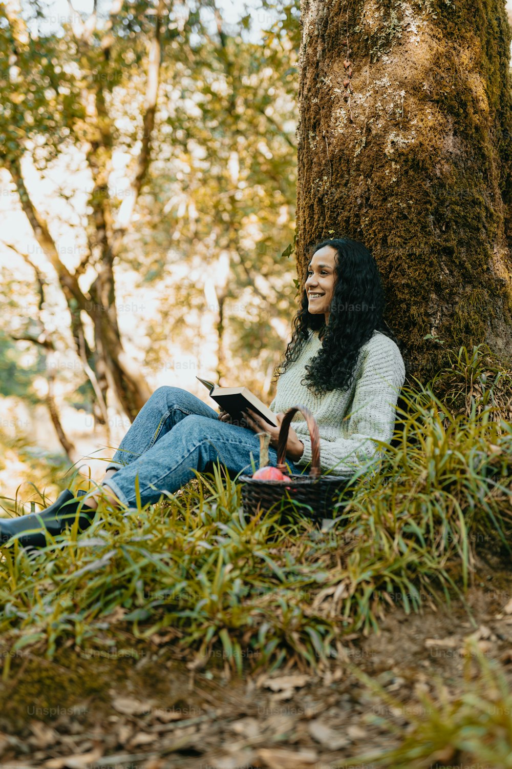 Una mujer sentada bajo un árbol leyendo un libro