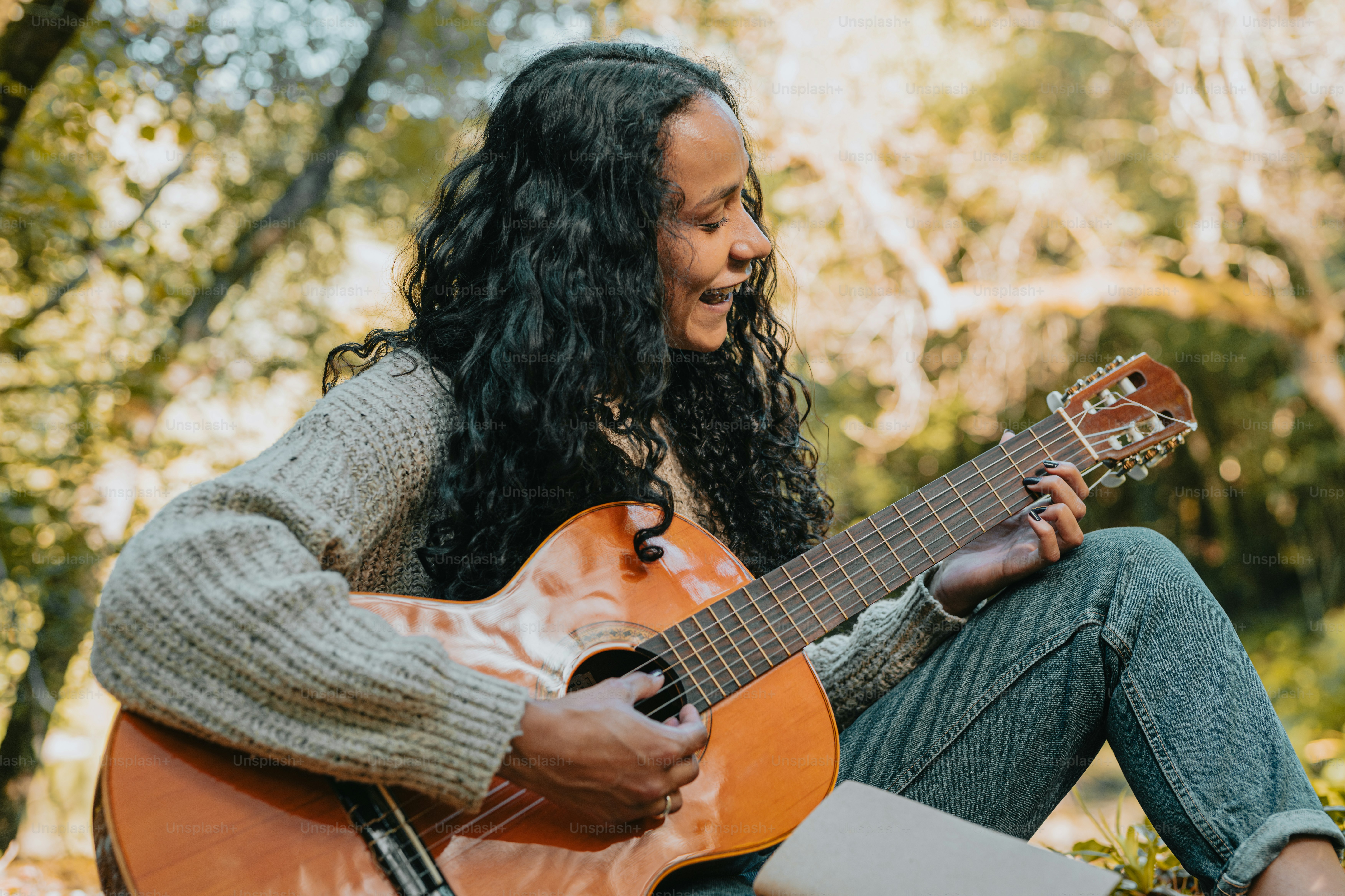 eine frau, die auf dem boden sitzt und gitarre spielt