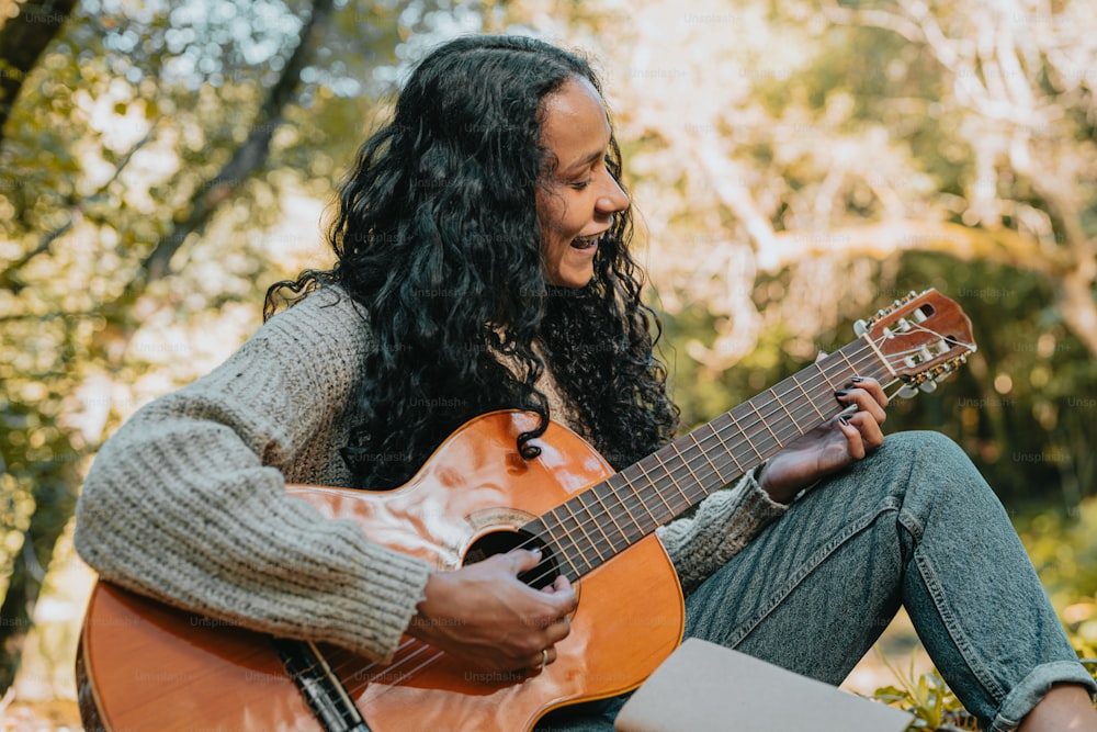 a woman sitting on the ground playing a guitar
