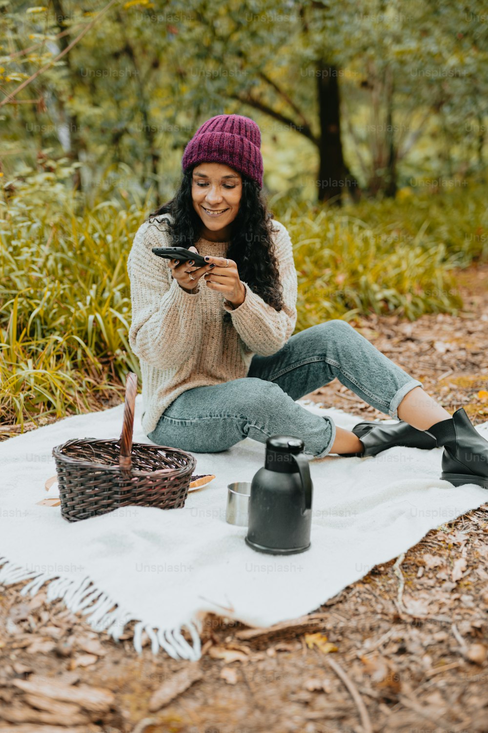 Una mujer sentada sobre una manta en el bosque