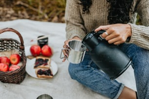 eine frau, die auf einer decke mit einer tasse kaffee sitzt