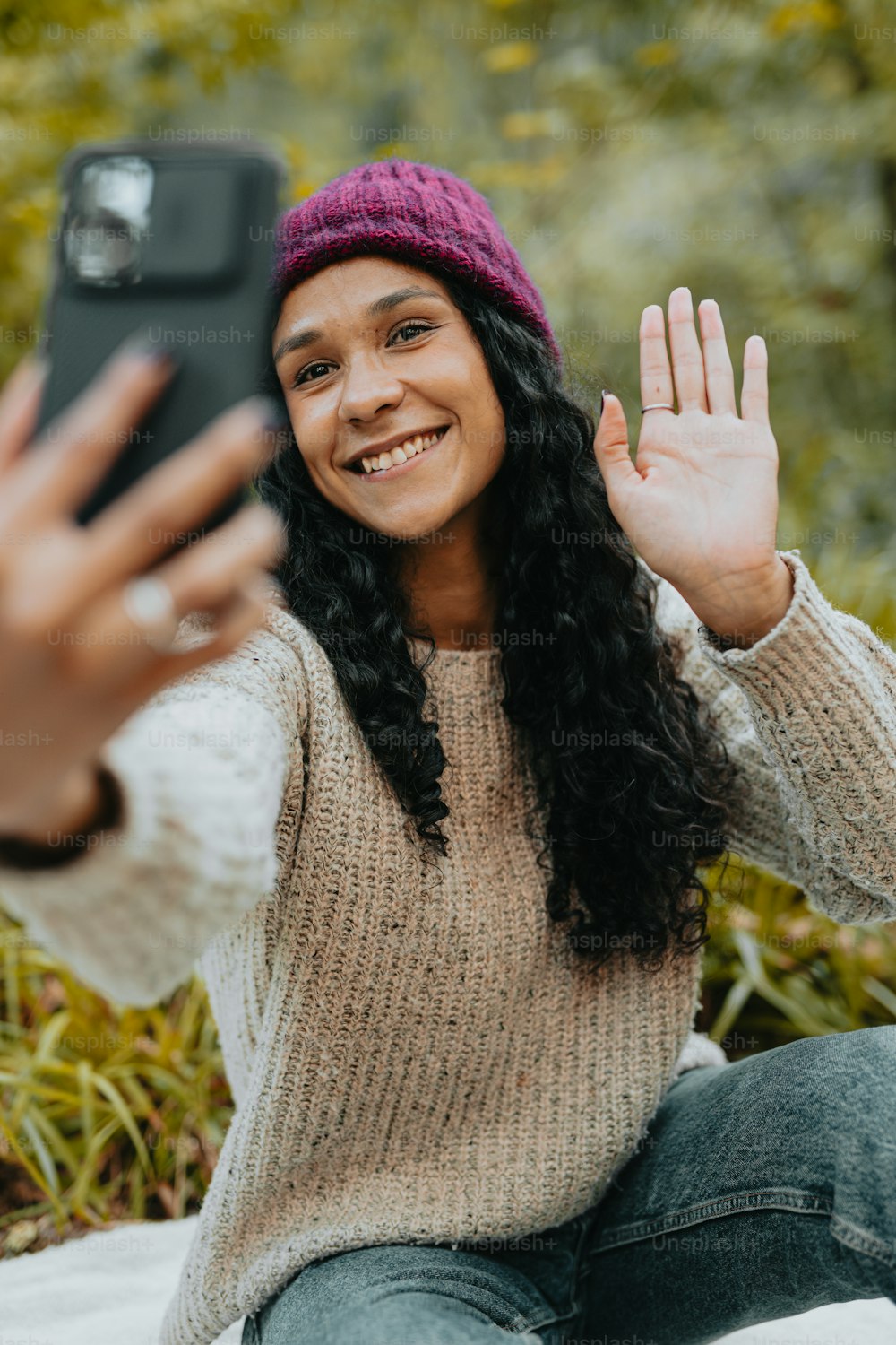 a woman sitting on the ground taking a picture with her phone
