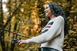 a woman smiles while holding a fishing rod