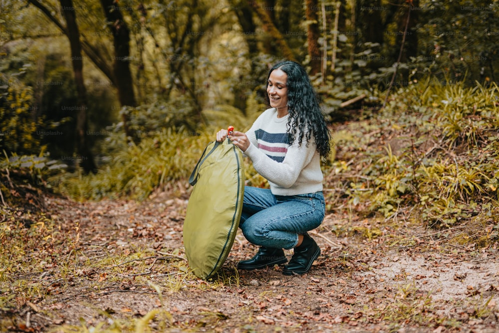 Una mujer arrodillada sosteniendo una bolsa verde